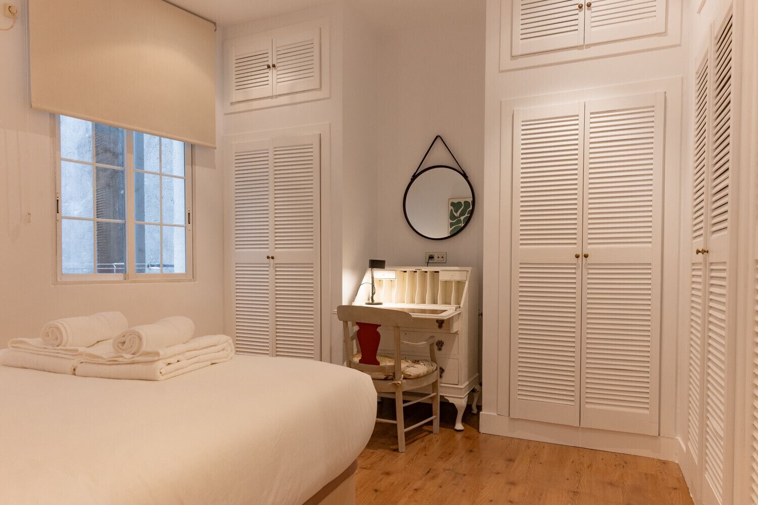 Une chambre à coucher avec un lit, une coiffeuse avec un miroir et des placards blancs.