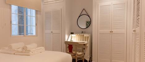 Une chambre à coucher avec un lit, une coiffeuse avec un miroir et des placards blancs.