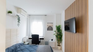 A modern bedroom with a bed, a desk, a chair, a TV, and a potted plant. - Paris: room with comfort, cosiness and shared areas Chamartín – Mauricio Legendre (Madrid)