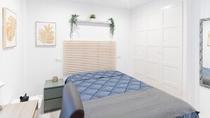 Et soveværelse med seng, natbord, kommode, loftventilator og en dør.
