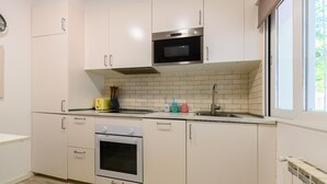 Una cocina moderna con armarios blancos, un microondas, un horno y un lavamanos.