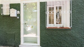 Una puerta con un panel de vidrio, un buzón pequeño y una ventana con una reja de metal.