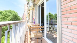 A balcony with a wooden table and chairs, a potted plant, and a view of greenery. - Studio with balcony - Everything you need for a perfect stay in Madrid (Madrid)