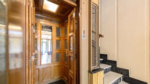 A wooden door with glass panels, a metal gate, and marble steps leading to an elevator. - Studio with balcony - Everything you need for a perfect stay in Madrid (Madrid)
