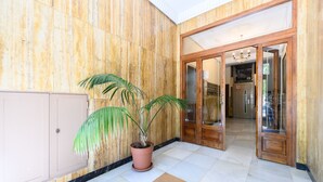 A lobby with a potted plant, a reception desk, and a wooden door leading to another room. - Studio with balcony - Everything you need for a perfect stay in Madrid (Madrid)