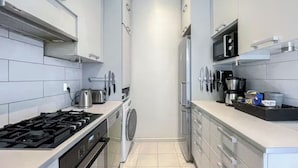A modern kitchen with a gas stove, microwave, and built-in oven. - 5 Room Apartment by the Esplanade Park (Helsinki)