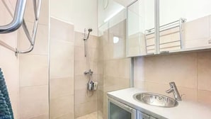 A modern bathroom with a glass shower enclosure, a sink with a mirror, and tiled walls. - 5 Room Apartment by the Esplanade Park (Helsinki)