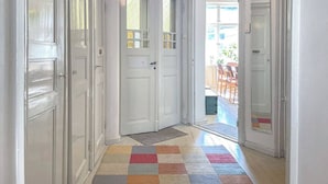 A hallway with white doors, a colorful rug, and a view of an outdoor patio area. - 5 Room Apartment by the Esplanade Park (Helsinki)