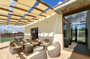 An outdoor patio with wicker furniture, a pergola, and a glass door leading to a balcony. - Modern Villa • Private Pool • River Views  • POV01 (Ayamonte)