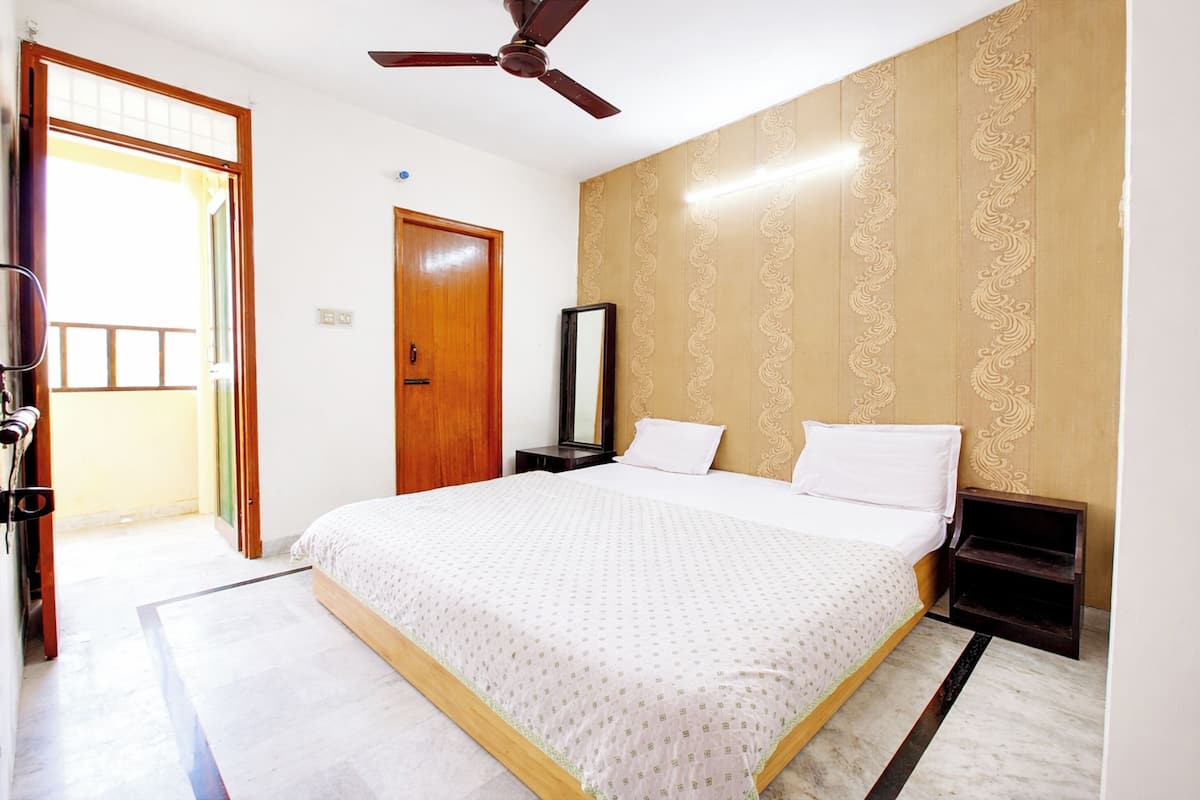 A bedroom with a bed, a ceiling fan, a door, and a wall with a decorative pattern.