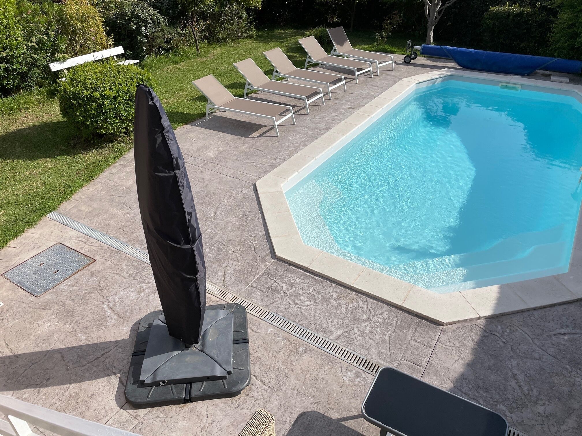 Ein Schwimmbecken mit Liegestühlen und einem Sonnenschirm.