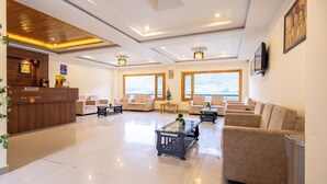 Eine großzügige Lobby mit einer Rezeption, mehreren Sitzbereichen und großen Fenstern mit Ausblick.