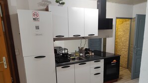 A compact kitchen with white cabinets, a black countertop, and a built-in oven. - 2-room apartment village center (Etaux)