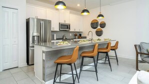A modern kitchen with a central island, stainless steel appliances, and pendant lighting. - Stylish Home & Free Resort Access 2420 (Kissimmee)
