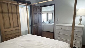 Een slaapkamer met een groot bed, een kaptafel en een deur naar een andere kamer.