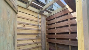 Een houten constructie met een lambrisering en een metalen douchekop.