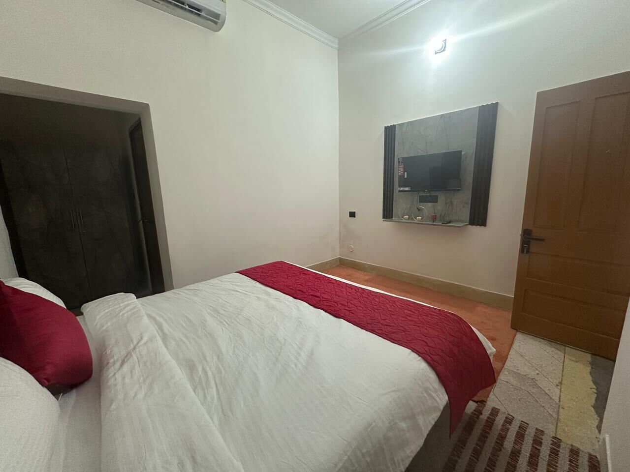 A room with two beds, a television mounted on the wall, and a door.