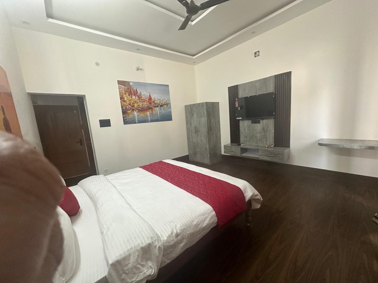 Een hotelkamer met een bed, een stadsgezicht op een schilderij, een marmeren kast en een televisie.