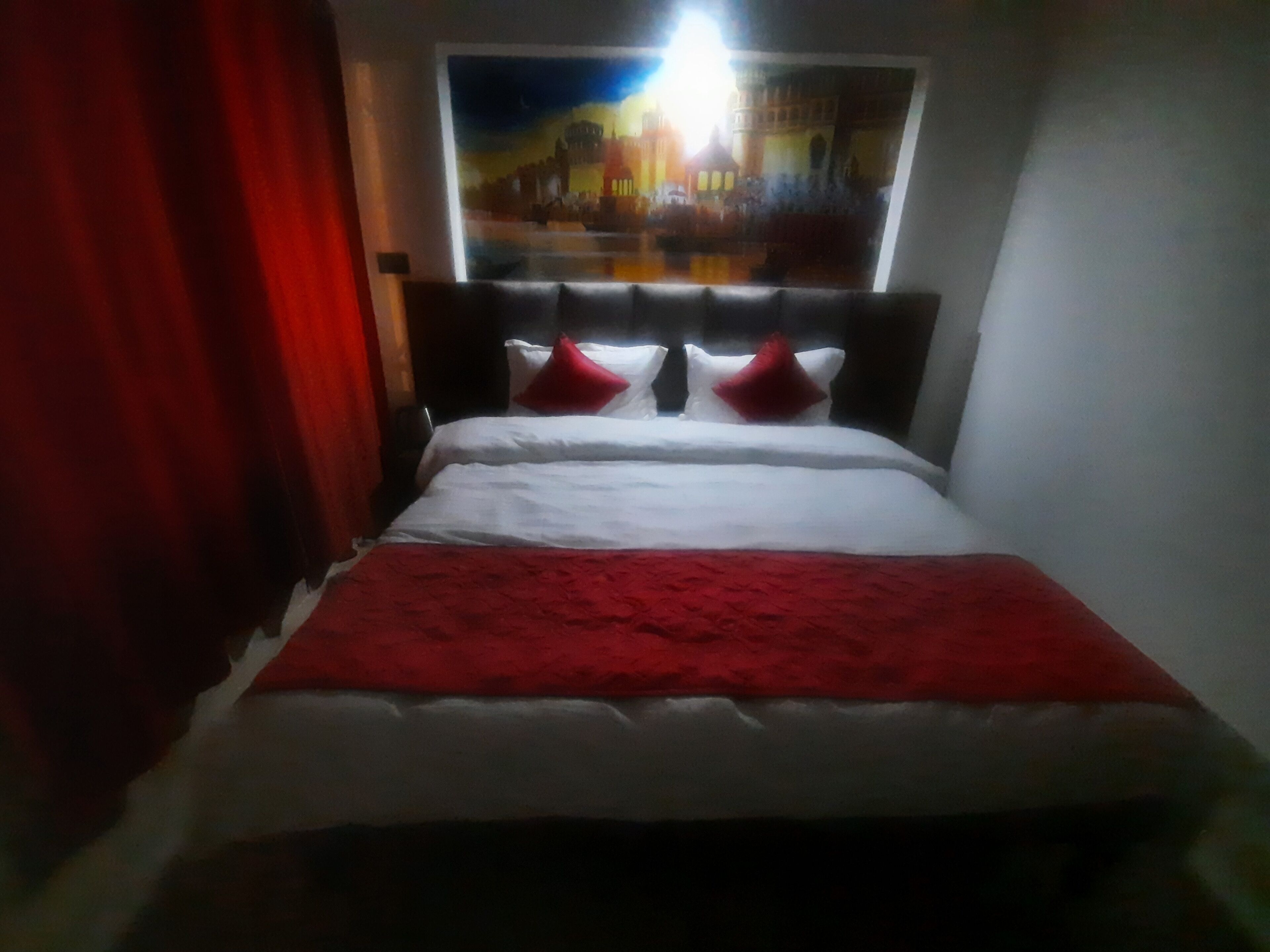 Ein Bett mit weißer und roter Bettwäsche, einer roten Tagesdecke und zwei roten Kissen.