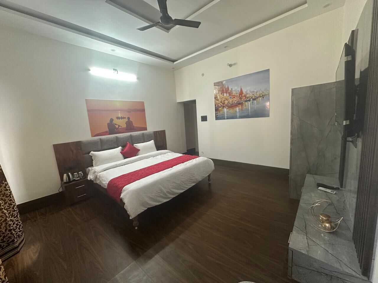 Une chambre d’hôtel avec un lit, une table de chevet, une télévision et un tableau au mur.