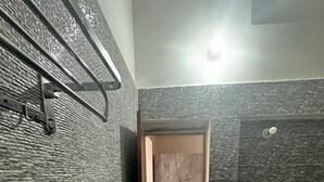 A bathroom with a wooden door, a toilet, and a towel rack. - Geetatri Luxury Homestay (Varanasi)