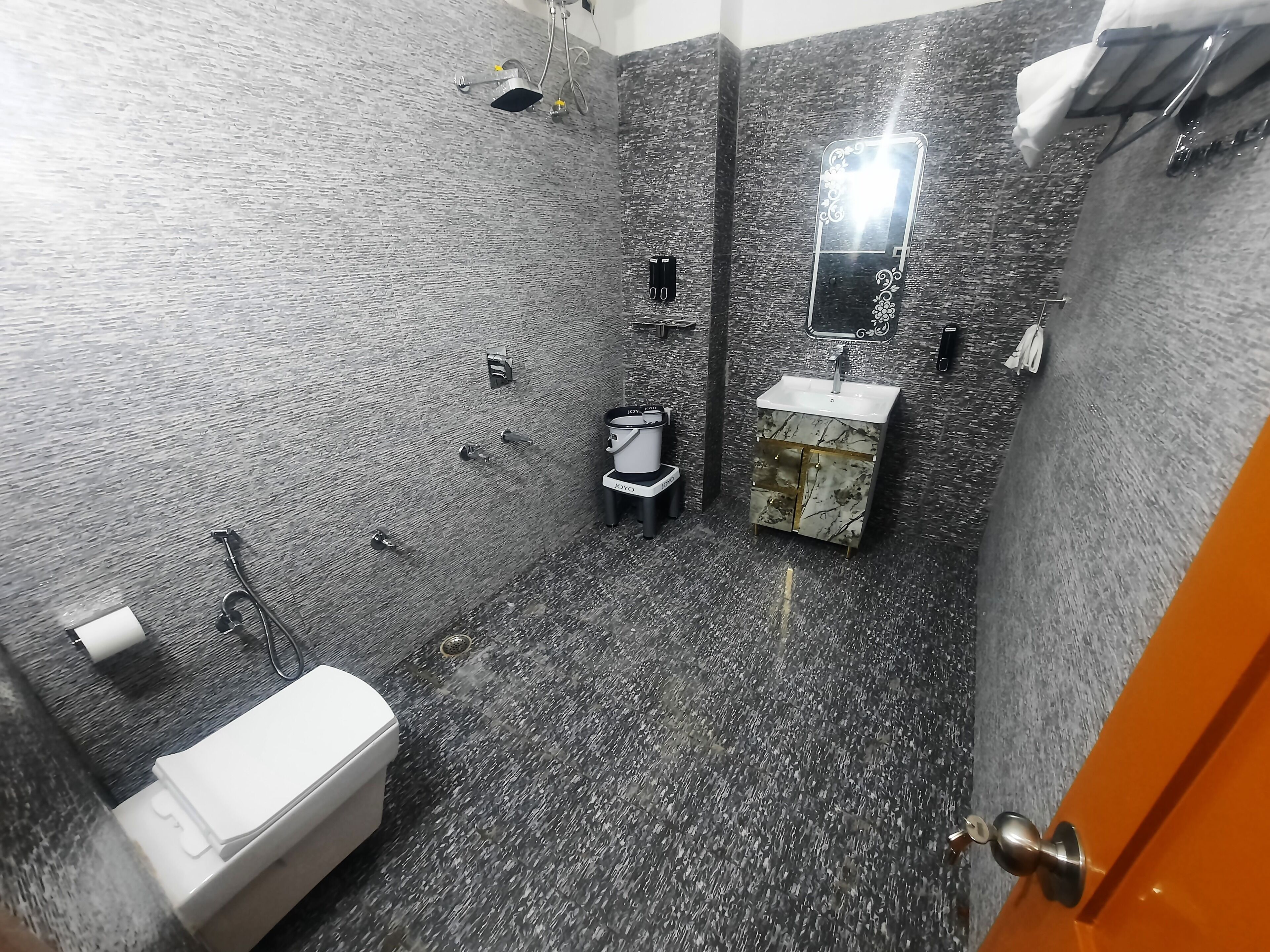 A bathroom with a textured wall, a sink, a toilet, and a shower.