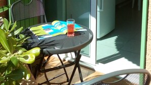A small patio with a table and chairs, a glass door leading to a room, and a refrigerator inside. - 50m sandy beach. All comforts ***. Quiet - Private parking - Air-conditioned (Hyères)