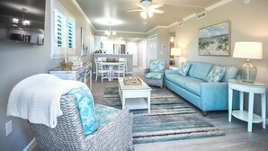 A spacious living room with a blue sofa, a white coffee table, and a patterned rug.