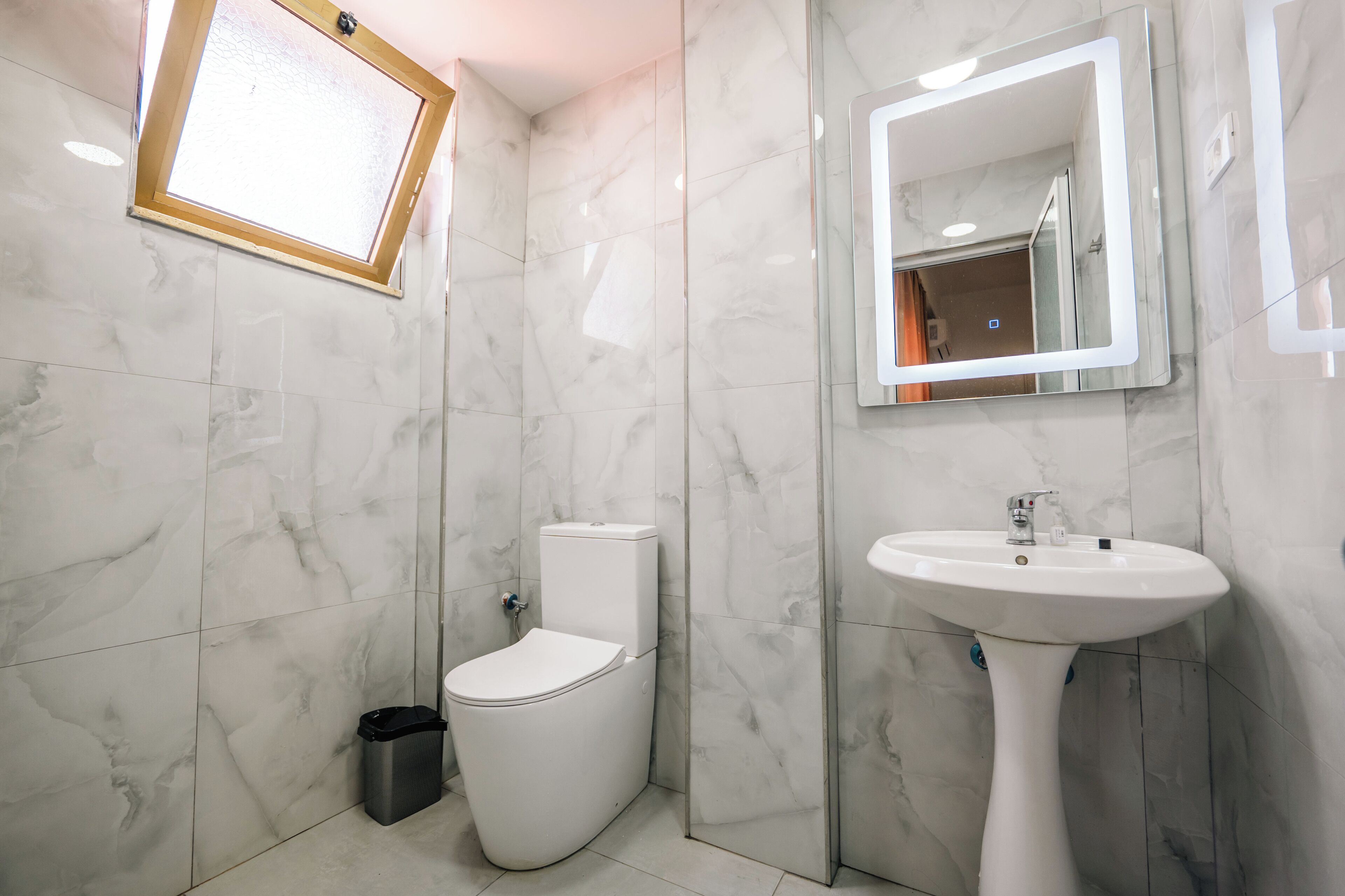 Une salle de bain avec des toilettes, un lavabo et un miroir.