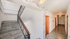 A hallway with a marble staircase and patterned wallpaper. - KURTI Hotel (Golem)