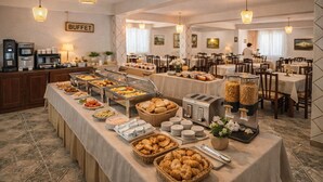 A buffet setup with various food items and a coffee station in a hotel dining area. - KURTI Hotel (Golem)
