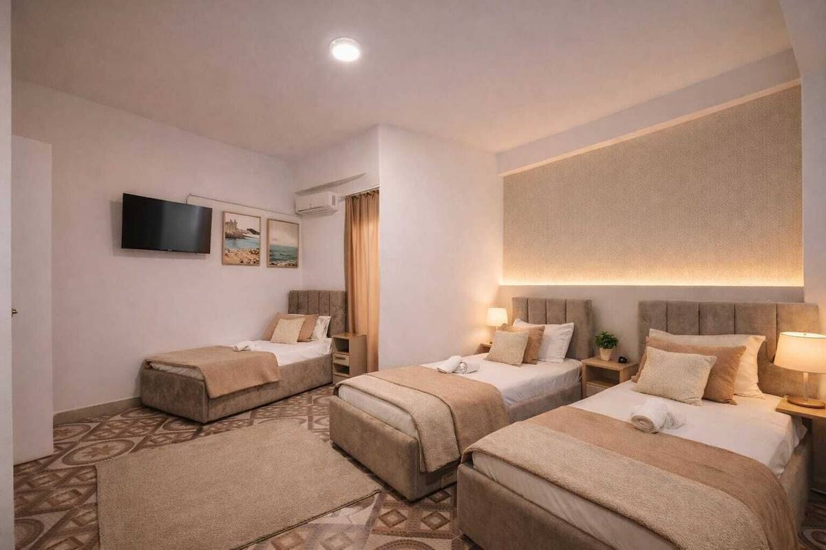 A hotel room with two beds, a TV, and a large window.