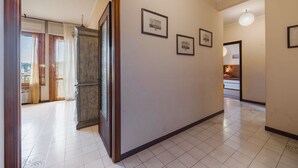 Un couloir avec une porte en bois, un sol carrelé et des tableaux encadrés accrochés au mur.