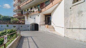 Un immeuble à plusieurs étages doté de balcons, d’un escalier et d’une entrée fermée par un portail.