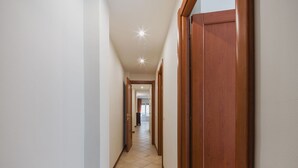 Un couloir étroit avec des portes en bois et des murs blancs.
