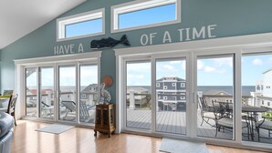 A spacious room with large windows, a view of the sea, and a sign that reads "HAVE A TIME OF A TIME". - Enjoy ocean views in "The Good Life" on Oak Island, featuring 5BR, private pool, and room for 17. (Oak Island)