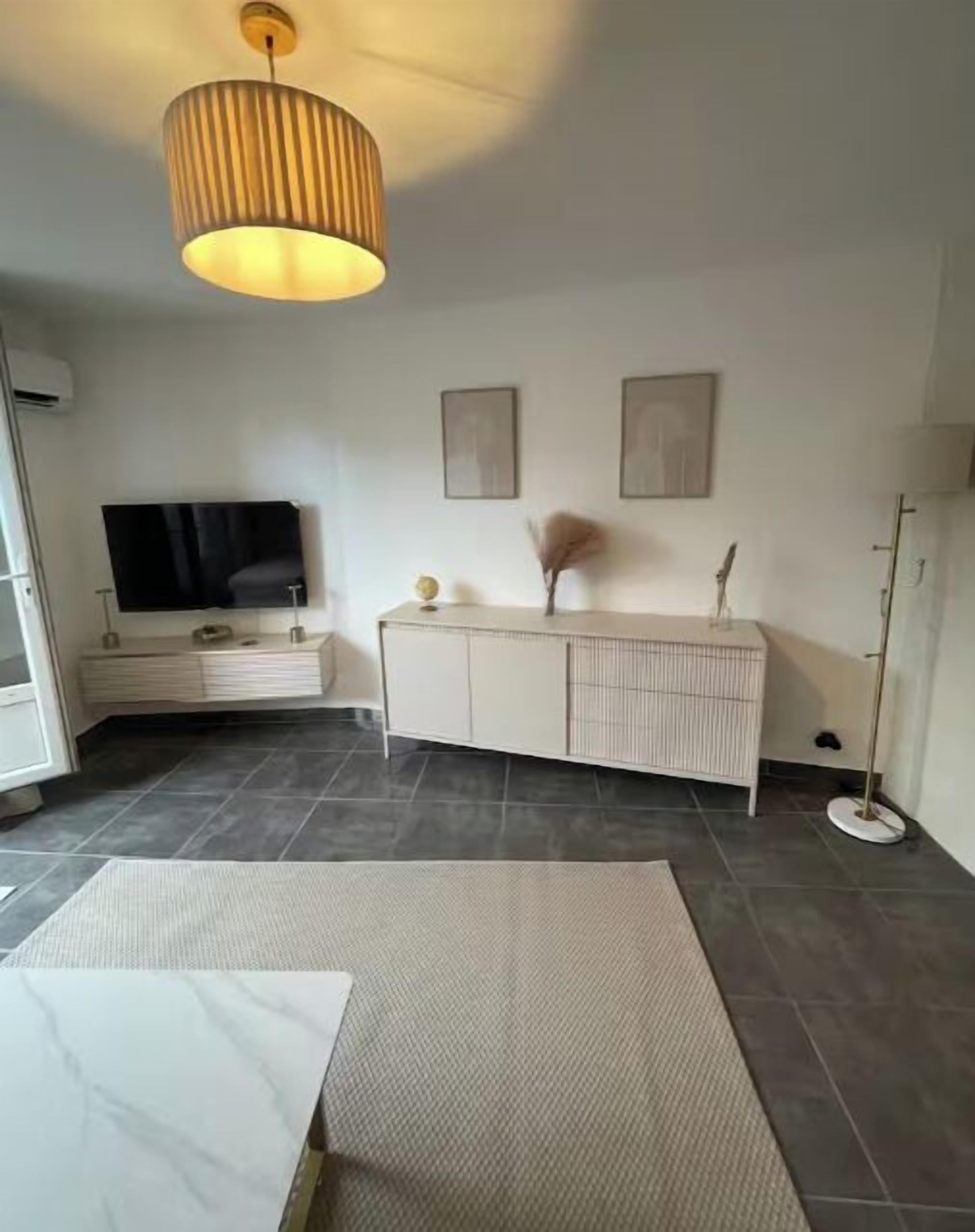 Una sala de estar moderna con un televisor de pantalla plana, un mueble blanco y una lámpara de pie.