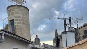 A narrow street with historic buildings, including a tower with a balcony and a spire in the background. - Tarascon center apartment (Tarascon)