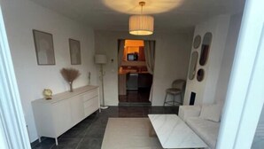 A modern living room with a sofa set, a dining table, and a kitchen area visible through an open door. - Tarascon center apartment (Tarascon)
