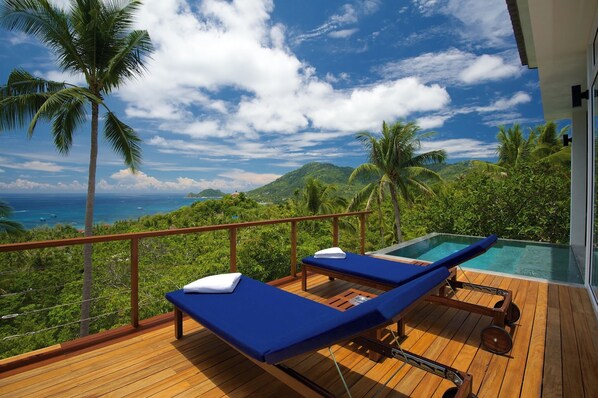 A wooden deck with two blue lounge chairs and a small pool, overlooking a lush landscape with palm trees and a view of the ocean. - Overthemoon Luxury Pool Villas (Koh Tao)
