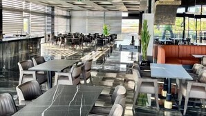 Un restaurante moderno con suelo de mármol, mesas altas y asientos acolchados.
