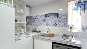 A compact kitchen with white cabinets, a built-in dishwasher, and a tiled backsplash.