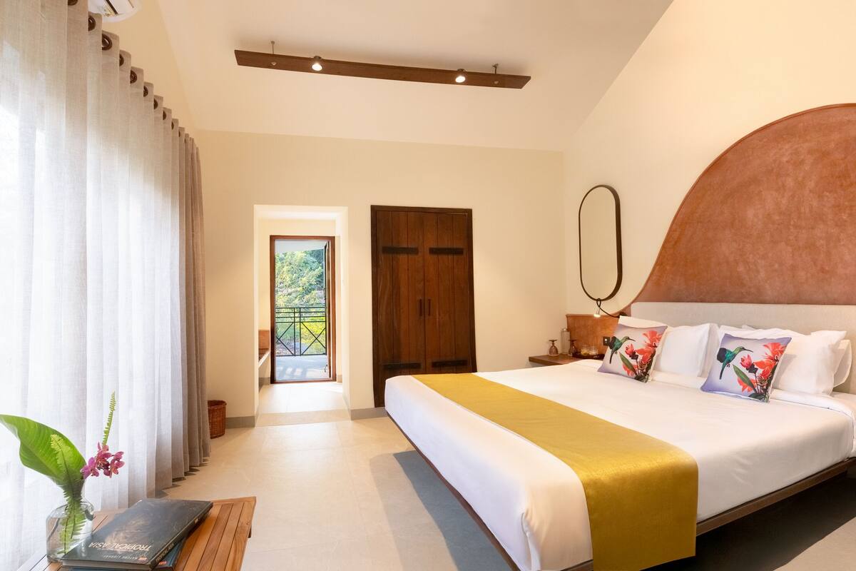 Ein Schlafzimmer mit einem großen Bett, einem Holzschrank, einem Nachttisch mit Lampe und Blick auf einen Balkon.
