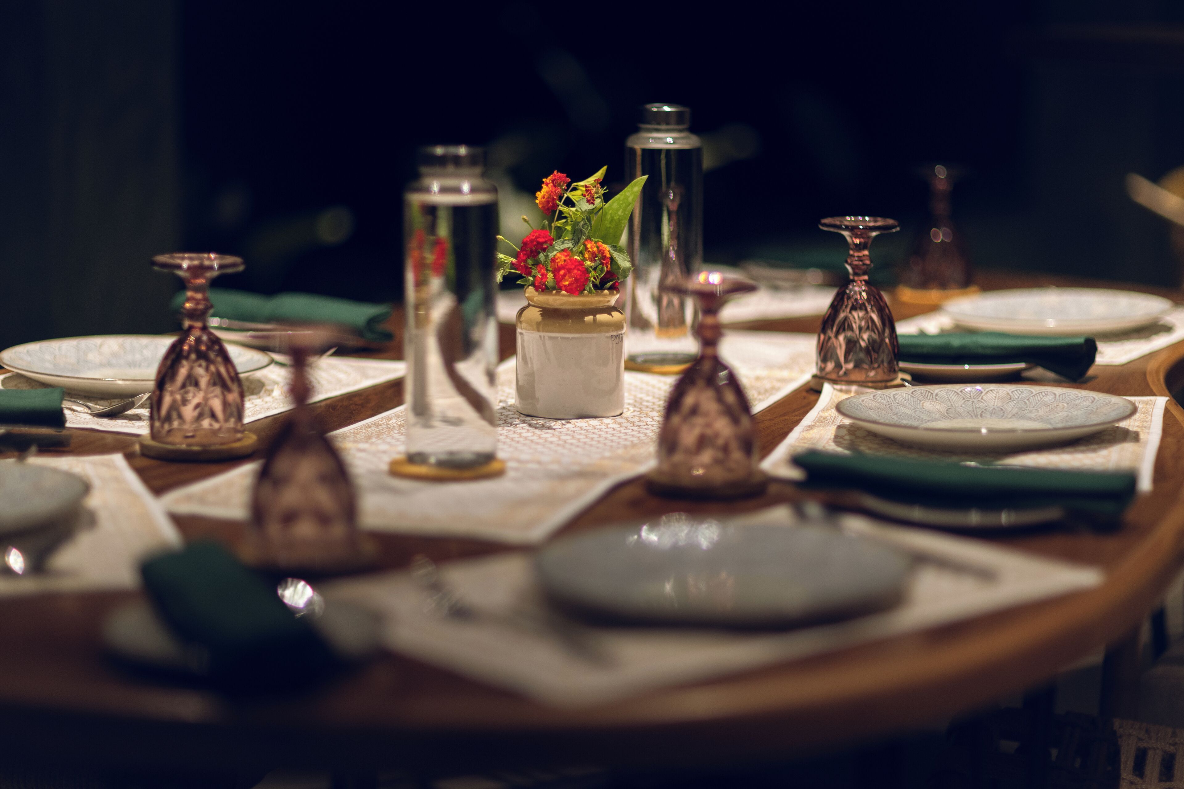 Une table à manger dressée avec des assiettes, des couverts et un centre de table agrémenté de fleurs.