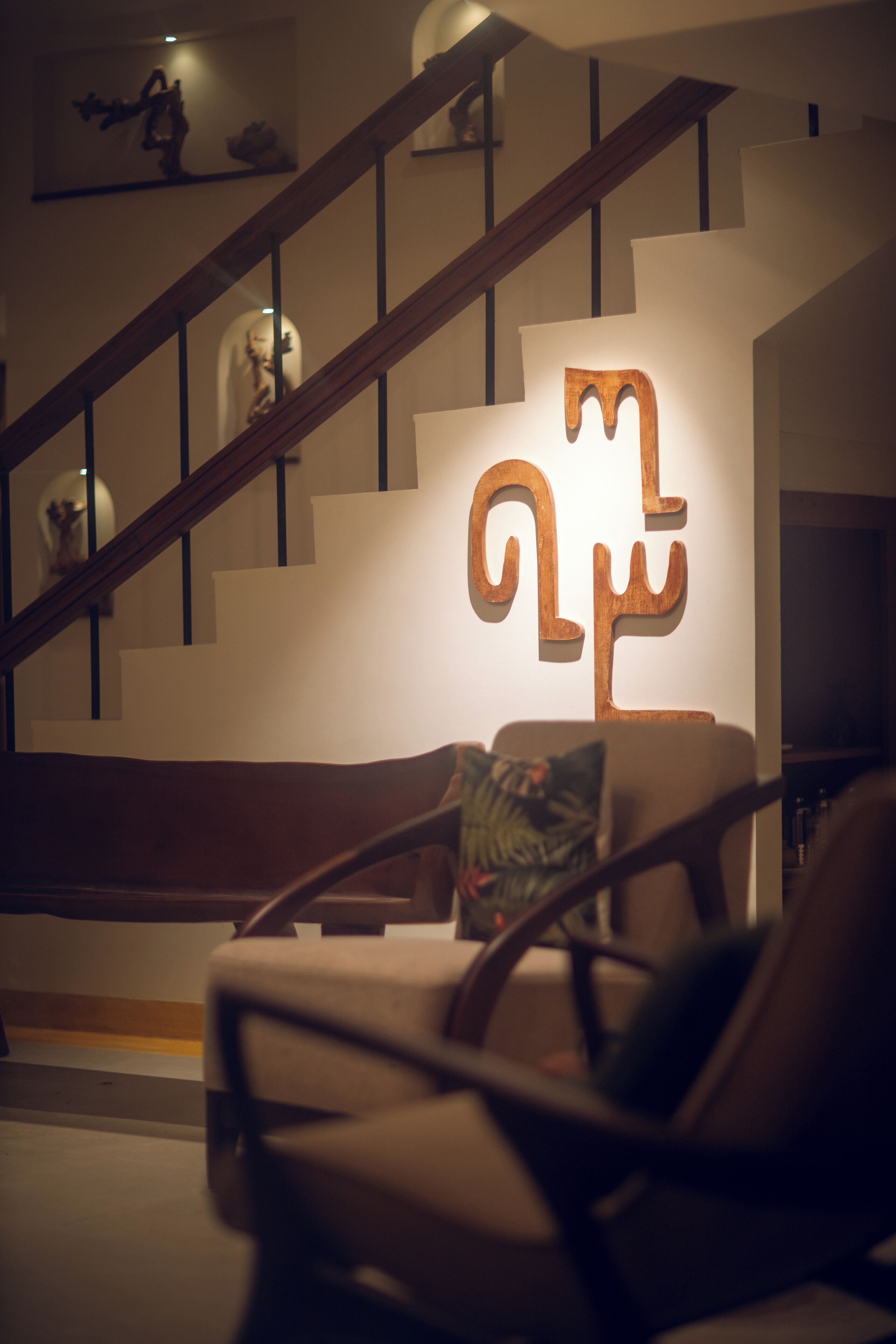 A staircase with a wooden handrail and a wall-mounted sculpture.