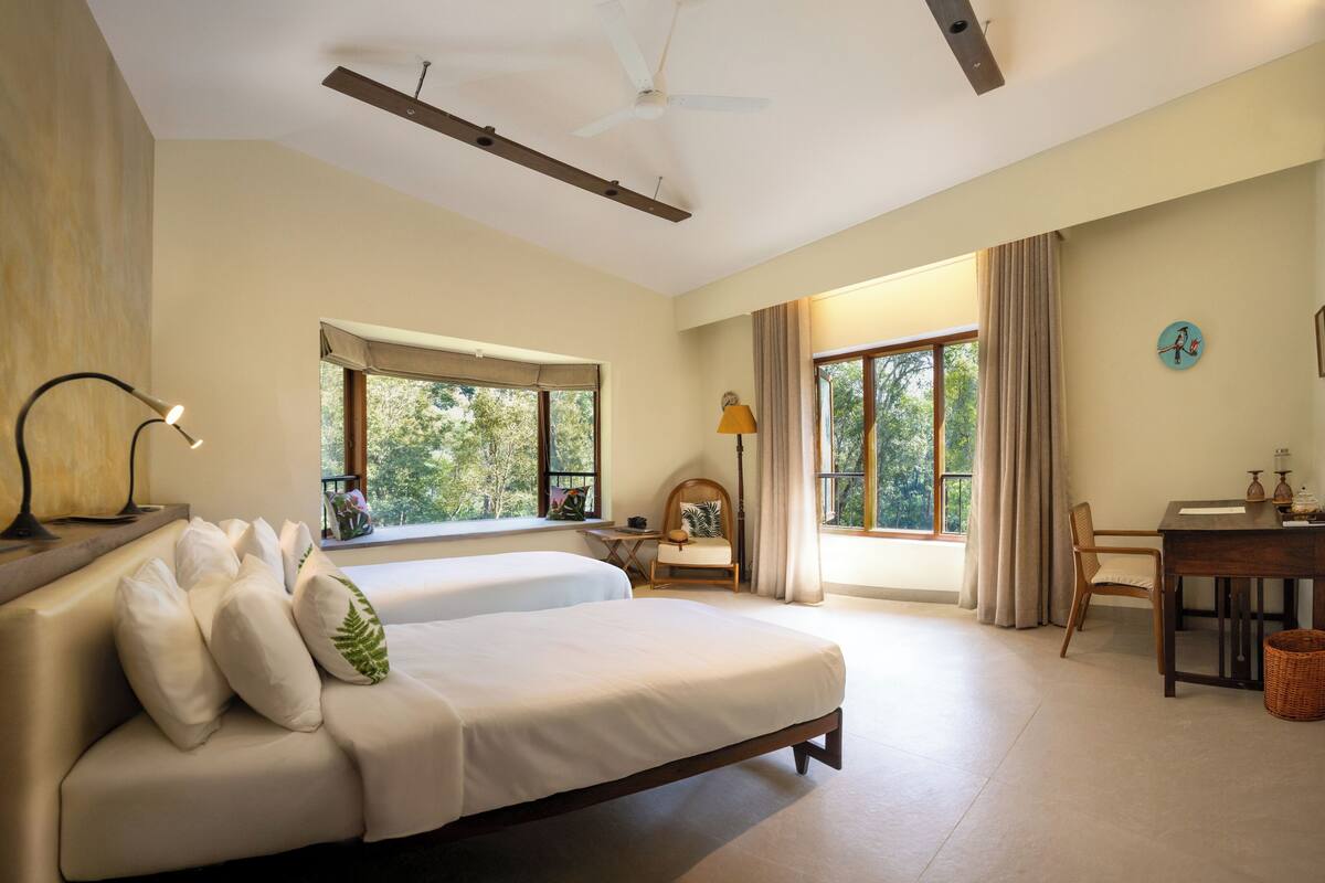 Ein geräumiges Schlafzimmer mit einem großen Bett, einem Schreibtisch und einem Stuhl. Fenster sorgen für natürliches Licht und einen Ausblick ins Freie.