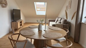 A modern dining area with a round wooden table, six chairs, and a central decorative vase. - GIPFELGLÜCK - Apartment centrally located in Nesselwang - KÖNIGSKARTE  (Nesselwang)