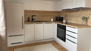 A modern kitchen with white cabinets, a wooden countertop, a black stove, and a coffee maker. - GIPFELGLÜCK - Apartment centrally located in Nesselwang - KÖNIGSKARTE  (Nesselwang)