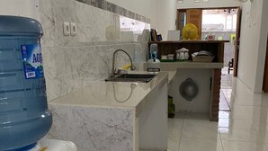Una cocina moderna con salpicadero de mármol, dispensador de agua, pileta y una pequeña isla con ventilador.