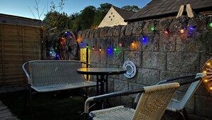 An outdoor patio area with wicker furniture, a round table, and decorative string lights. - Charming pottery barn conversion 2 mins from Horsforth train station. (Horsforth)